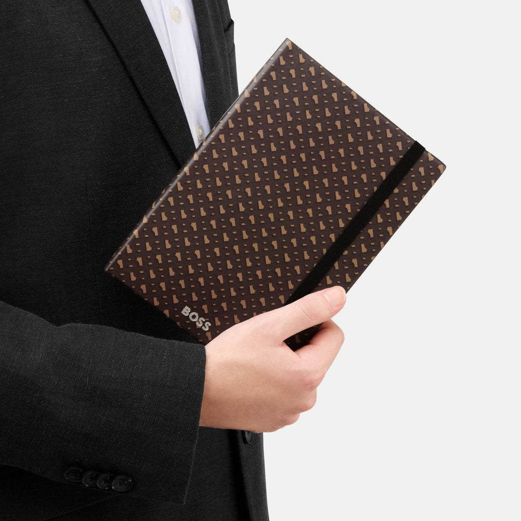 Person holding a patterned brown clutch with 'BOSS' branding.